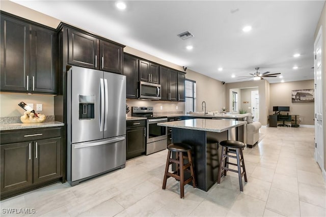 kitchen with visible vents, a breakfast bar, open floor plan, a center island, and stainless steel appliances