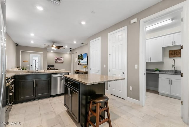 kitchen with appliances with stainless steel finishes, a center island, a sink, and a kitchen bar