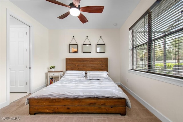 carpeted bedroom with ceiling fan and baseboards