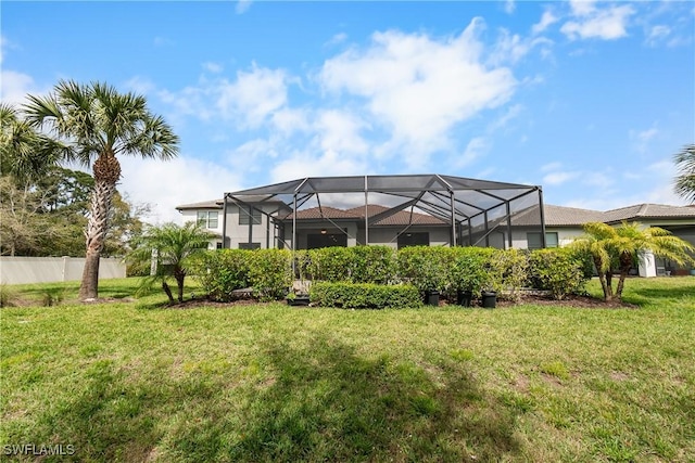 rear view of house with a yard, fence, and a lanai