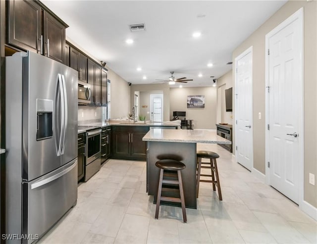 kitchen with visible vents, stainless steel appliances, dark brown cabinets, a kitchen bar, and recessed lighting