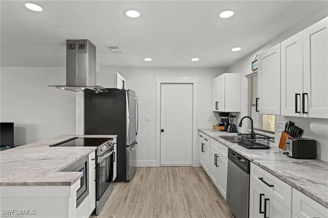 kitchen with light wood finished floors, visible vents, island range hood, appliances with stainless steel finishes, and white cabinetry