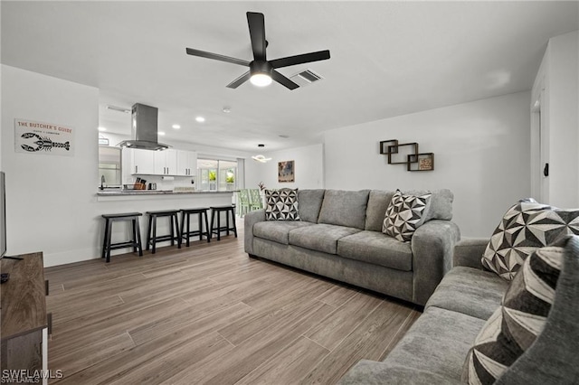 living room featuring baseboards, ceiling fan, visible vents, and wood finished floors