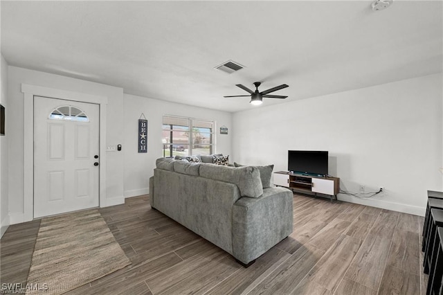 living area with visible vents, ceiling fan, baseboards, and wood finished floors