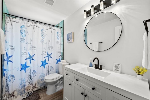 bathroom with toilet, a shower with shower curtain, wood finished floors, vanity, and visible vents