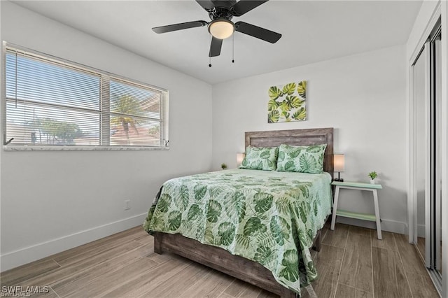 bedroom with a ceiling fan, a closet, baseboards, and wood finished floors