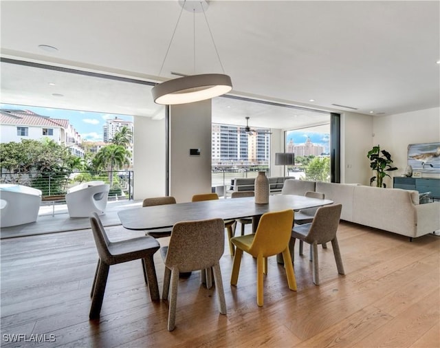 dining room with a wall of windows and light wood finished floors