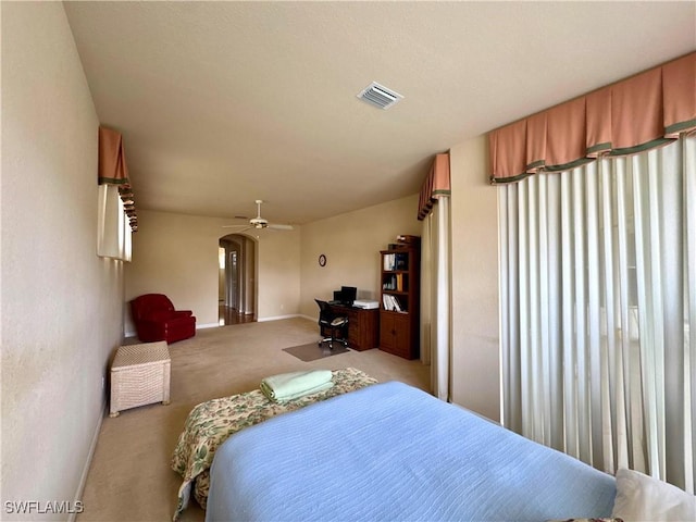 carpeted bedroom with arched walkways, visible vents, and baseboards