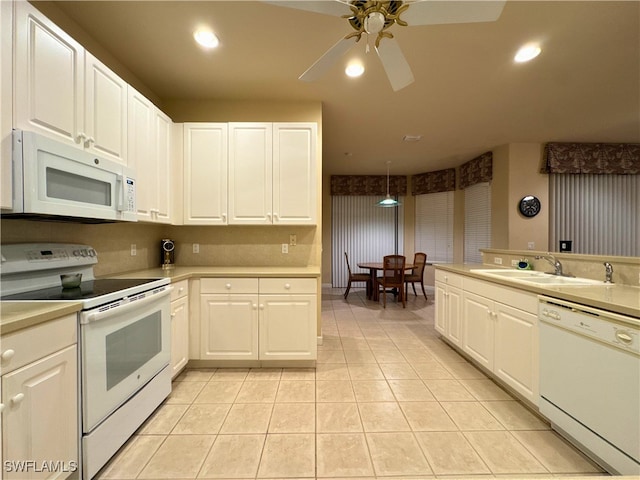 kitchen with white appliances, white cabinets, a sink, and light countertops