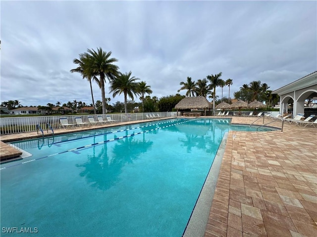 community pool with a patio area and fence