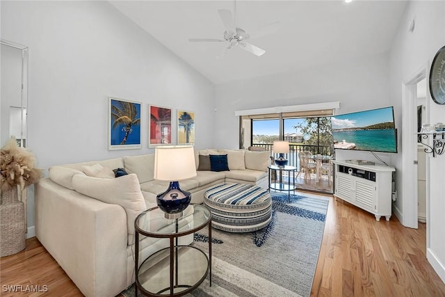 living area featuring ceiling fan, high vaulted ceiling, baseboards, and light wood-style floors