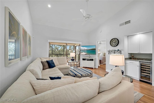 living room featuring high vaulted ceiling, wine cooler, light wood-type flooring, and visible vents