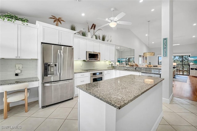 kitchen featuring light tile patterned floors, stainless steel appliances, white cabinetry, and a center island