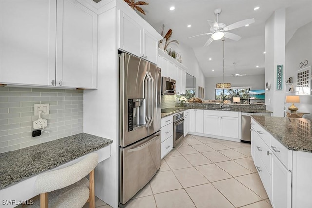 kitchen with light tile patterned floors, stainless steel appliances, dark stone countertops, and white cabinetry