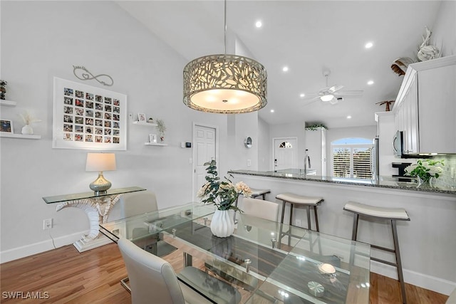 dining room featuring lofted ceiling, recessed lighting, wood finished floors, a ceiling fan, and baseboards