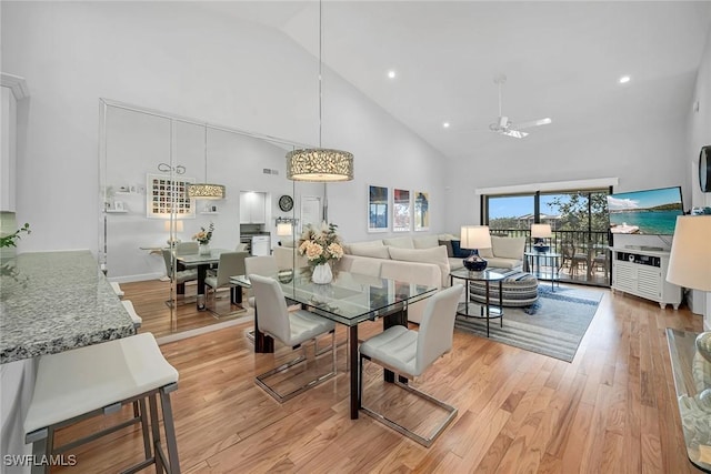 dining room with high vaulted ceiling, light wood-type flooring, and a ceiling fan