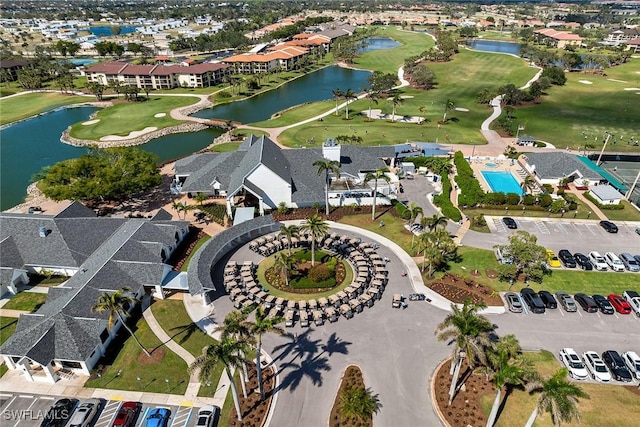 drone / aerial view featuring golf course view, a water view, and a residential view