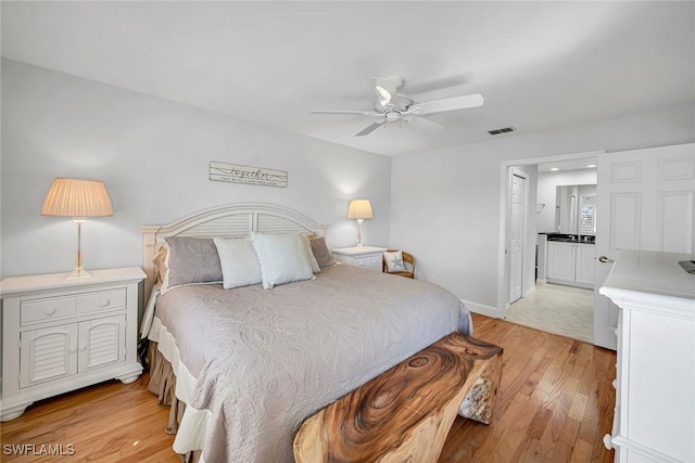 bedroom featuring ceiling fan, light wood-style flooring, visible vents, and baseboards