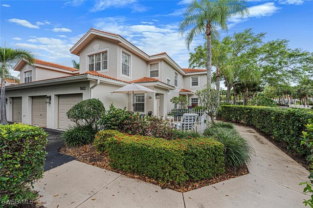 mediterranean / spanish house featuring aphalt driveway, stucco siding, an attached garage, fence, and a tiled roof