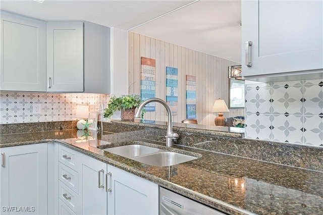 kitchen featuring dishwasher, decorative backsplash, dark stone counters, and a sink