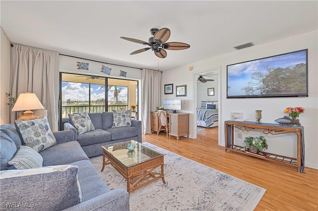 living room with light wood-style floors, ceiling fan, and visible vents