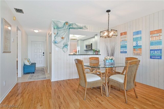 dining room with a chandelier, visible vents, and light wood-style flooring