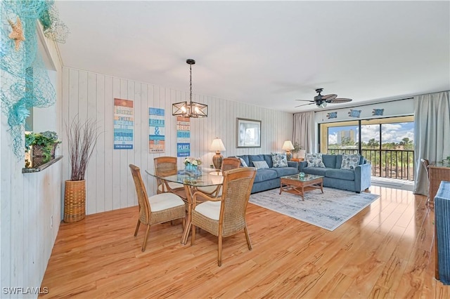 dining area featuring ceiling fan with notable chandelier and light wood-type flooring