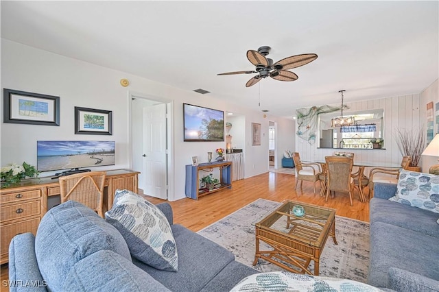 living room featuring ceiling fan with notable chandelier, wood finished floors, and visible vents