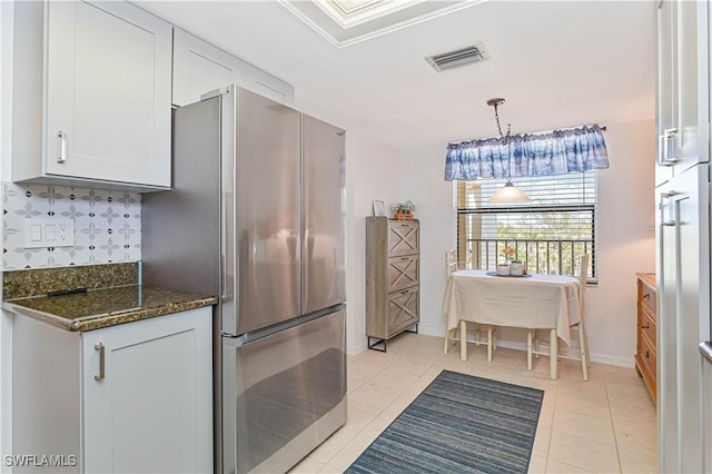 kitchen with light tile patterned floors, visible vents, backsplash, freestanding refrigerator, and dark stone counters