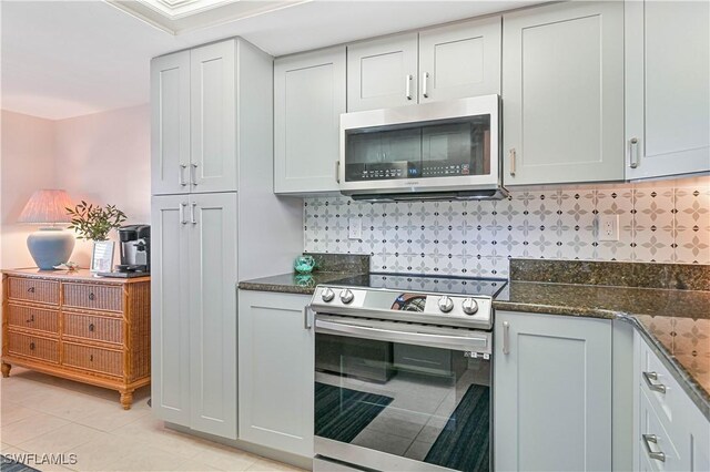 kitchen featuring tasteful backsplash, dark stone counters, stainless steel appliances, and light tile patterned flooring