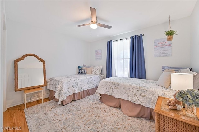 bedroom featuring wood finished floors, a ceiling fan, and baseboards