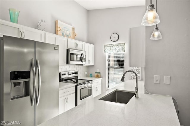 kitchen with appliances with stainless steel finishes, white cabinets, a sink, and tasteful backsplash