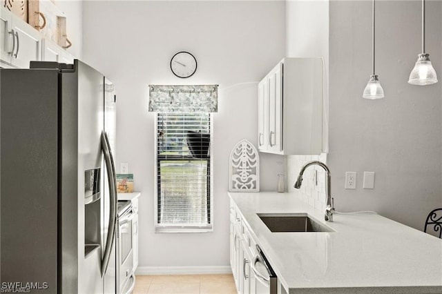 kitchen with tasteful backsplash, white cabinets, stainless steel appliances, light countertops, and a sink