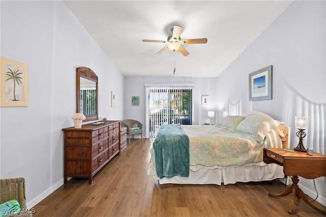 bedroom featuring vaulted ceiling, baseboards, wood finished floors, and access to exterior