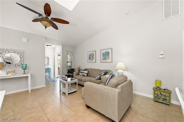 living area featuring light tile patterned floors, ceiling fan, visible vents, baseboards, and lofted ceiling with skylight