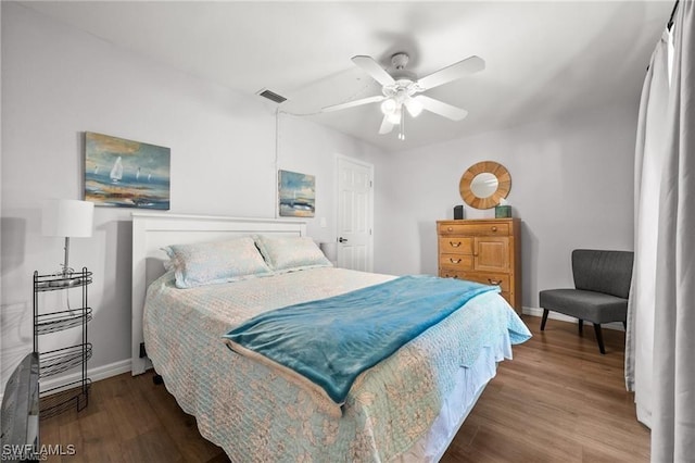 bedroom featuring a ceiling fan, visible vents, baseboards, and wood finished floors