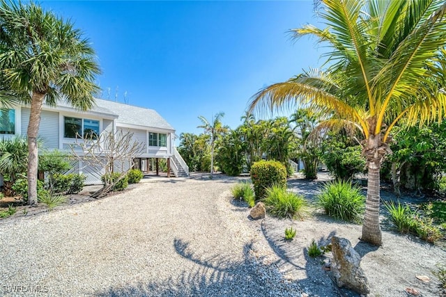 view of yard featuring driveway and stairs