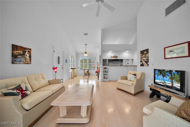 living room with light wood finished floors, a ceiling fan, visible vents, and high vaulted ceiling