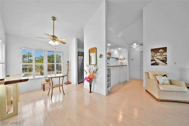 living area featuring high vaulted ceiling, ceiling fan, baseboards, and wood finished floors