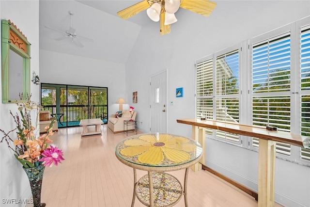 interior space featuring high vaulted ceiling, baseboards, a ceiling fan, and wood finished floors