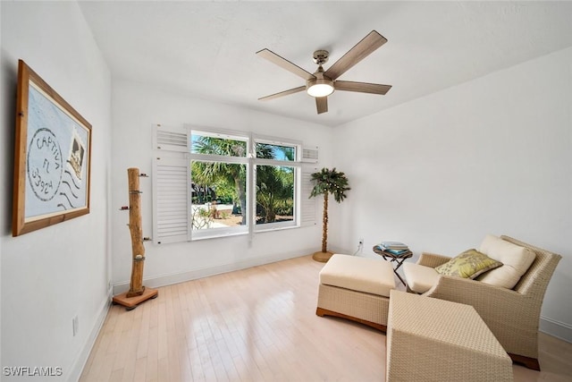 living area featuring a ceiling fan, baseboards, and wood finished floors