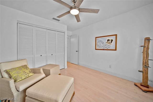 sitting room with baseboards, light wood-style flooring, visible vents, and a ceiling fan