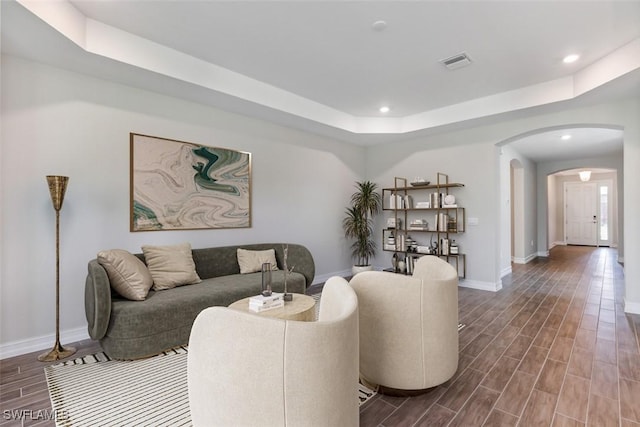 living room with arched walkways, recessed lighting, visible vents, wood tiled floor, and a tray ceiling