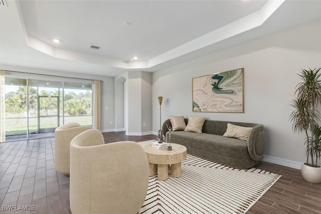 living room with recessed lighting, wood finish floors, visible vents, baseboards, and a tray ceiling