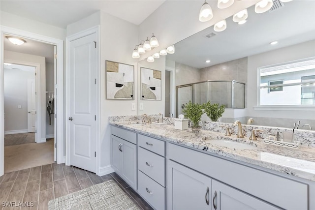 bathroom with visible vents, a sink, a shower stall, and double vanity