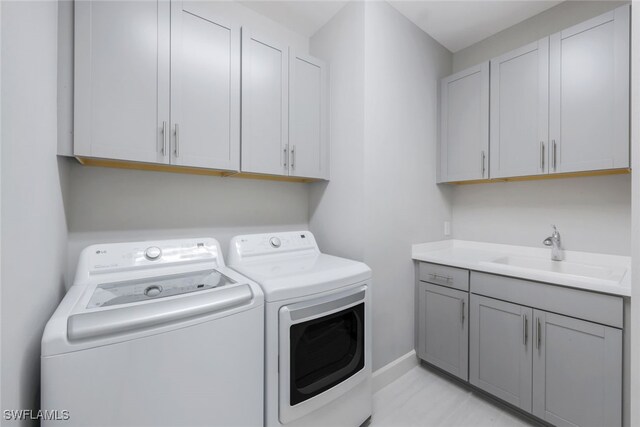 laundry room with independent washer and dryer, cabinet space, a sink, and baseboards