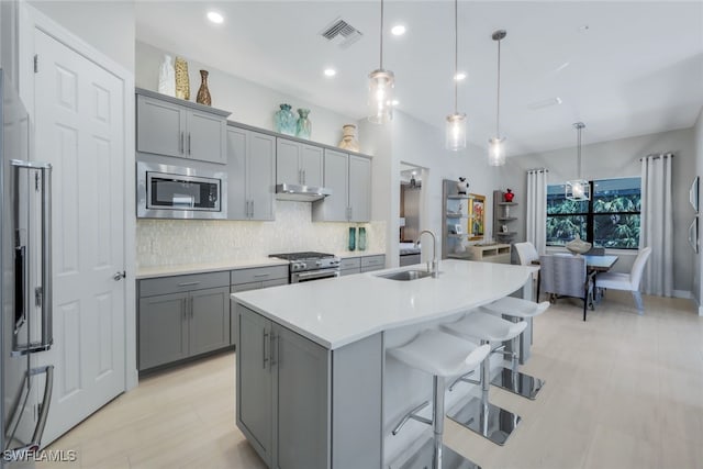 kitchen with under cabinet range hood, gray cabinetry, a sink, visible vents, and appliances with stainless steel finishes