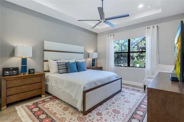 bedroom featuring baseboards, a raised ceiling, wood finished floors, and recessed lighting