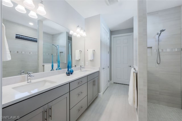 bathroom with double vanity, walk in shower, a sink, and visible vents