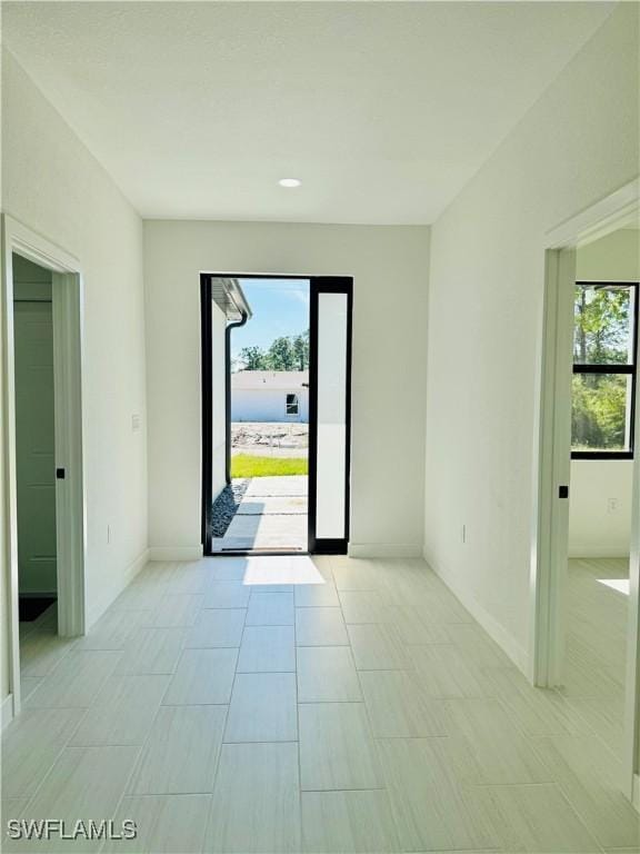 interior space featuring light tile patterned floors, plenty of natural light, and baseboards